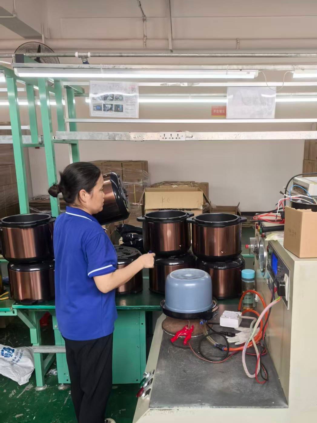 Worker assembling and testing rice cookers on a production line